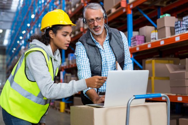 Worker And Manager Are Looking A Laptop In A Warehouse